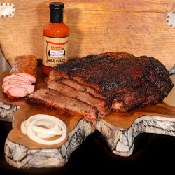 Cooper's Old Time Pit Bar-b-que mail order taster box includes brisket, pork tenderloin, and a bottle of bbq sauce. Displayed on a beautiful cutting board arrangement with garnishes.